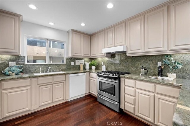 kitchen with light stone countertops, white dishwasher, dark hardwood / wood-style floors, sink, and stainless steel gas range