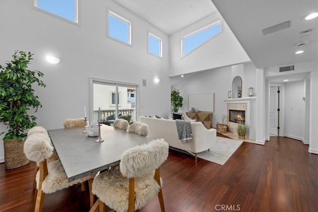 dining room with dark wood-type flooring and a towering ceiling