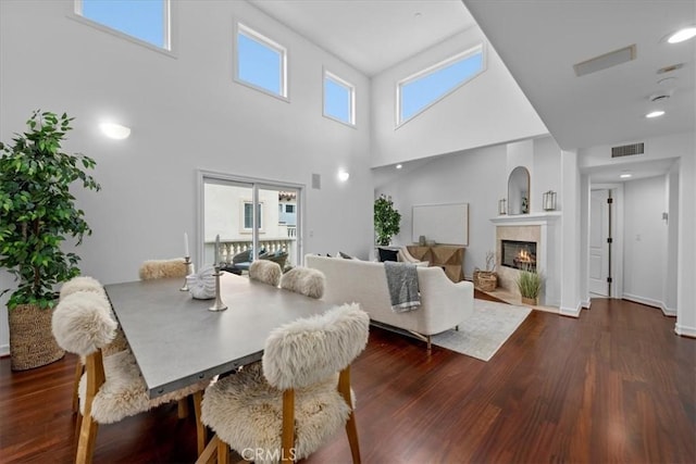 dining room with a fireplace, visible vents, dark wood-type flooring, and recessed lighting