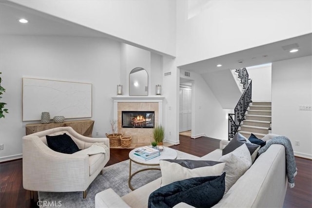 living area featuring stairs, a tile fireplace, recessed lighting, and wood finished floors