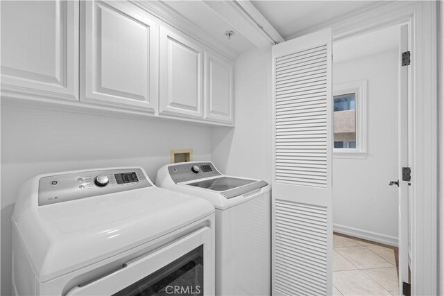 washroom with light tile patterned flooring, separate washer and dryer, and cabinets