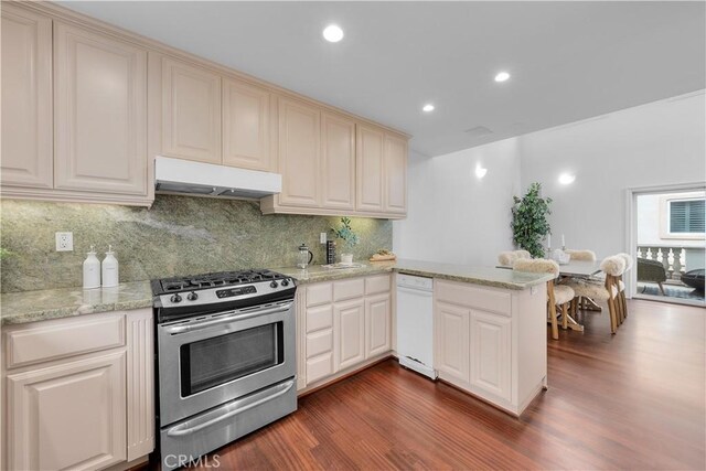 kitchen with dishwasher, gas stove, dark hardwood / wood-style flooring, kitchen peninsula, and decorative backsplash