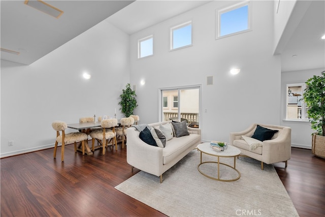 living room with a towering ceiling and dark hardwood / wood-style floors