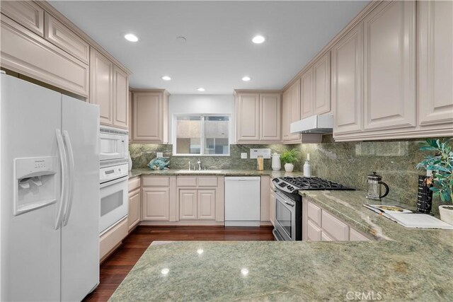 kitchen with sink, light stone countertops, white appliances, and dark hardwood / wood-style flooring