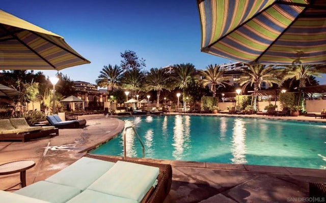 pool at dusk featuring a patio area