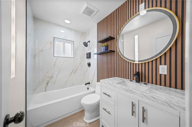 full bathroom featuring hardwood / wood-style floors, vanity, toilet, and tiled shower / bath