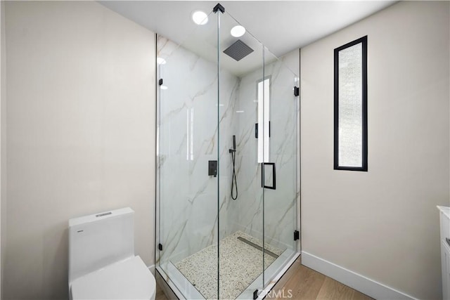 bathroom with wood-type flooring, a shower with shower door, and toilet