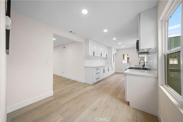 kitchen with white cabinets, sink, and light hardwood / wood-style flooring