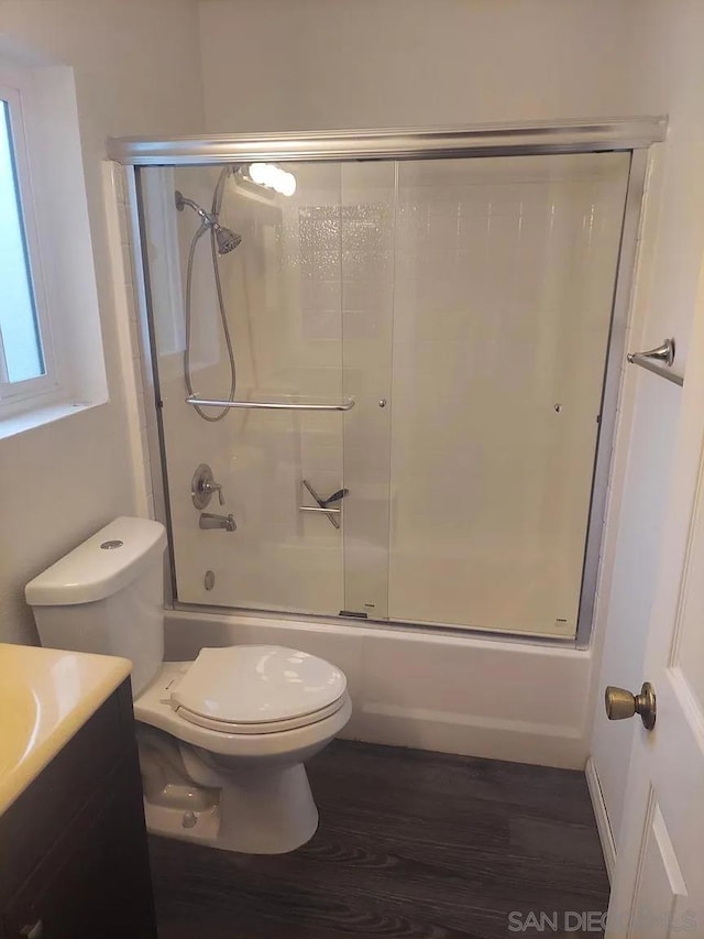 full bathroom with hardwood / wood-style flooring, vanity, toilet, and enclosed tub / shower combo