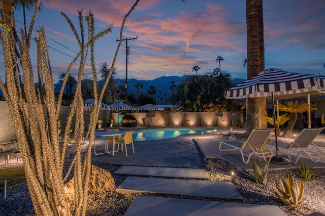 pool at dusk featuring a mountain view and a patio area