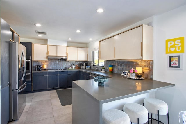 kitchen featuring sink, stainless steel appliances, tasteful backsplash, kitchen peninsula, and a kitchen bar