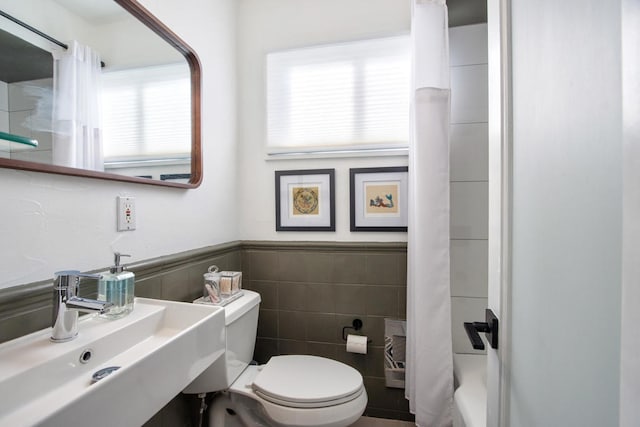 bathroom featuring toilet, tile walls, and sink