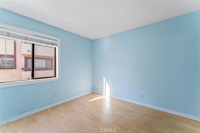 unfurnished room with a textured ceiling and light wood-type flooring