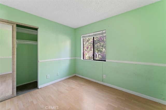 unfurnished bedroom featuring a closet, light hardwood / wood-style floors, and a textured ceiling