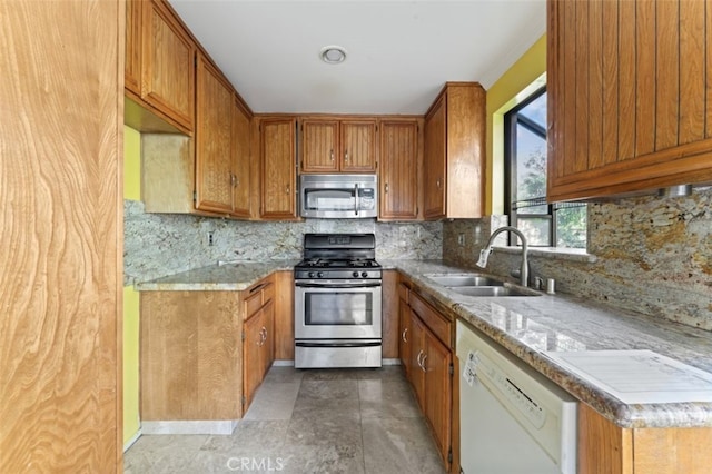 kitchen with tasteful backsplash, light stone countertops, sink, and appliances with stainless steel finishes