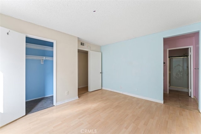 unfurnished bedroom featuring a closet, a textured ceiling, and light hardwood / wood-style flooring