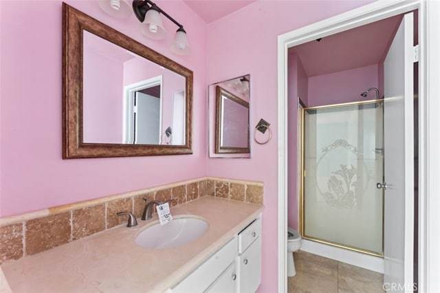 bathroom featuring tile patterned flooring, vanity, a shower with shower door, and toilet