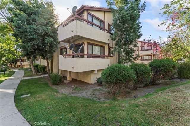 view of side of property with a lawn and a balcony