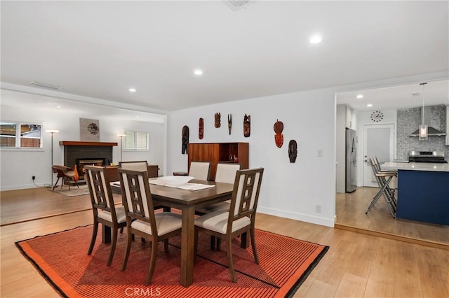 dining area with a fireplace and light hardwood / wood-style floors