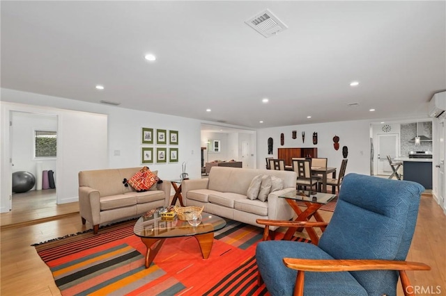 living room with light wood-type flooring and a wall mounted air conditioner