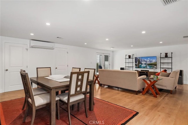 dining space featuring a wall unit AC and wood-type flooring