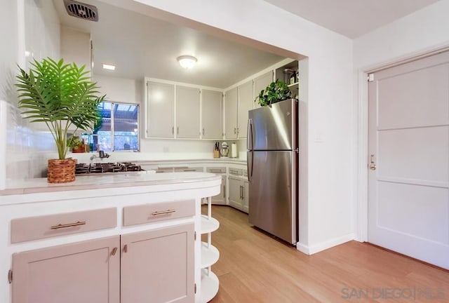 kitchen featuring stainless steel fridge, sink, and light hardwood / wood-style flooring