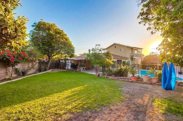 yard at dusk featuring a balcony and a patio area