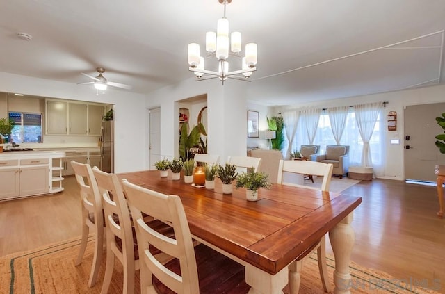 dining room featuring ceiling fan with notable chandelier and light hardwood / wood-style floors