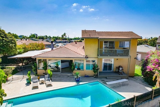 rear view of house featuring a patio and a fenced in pool