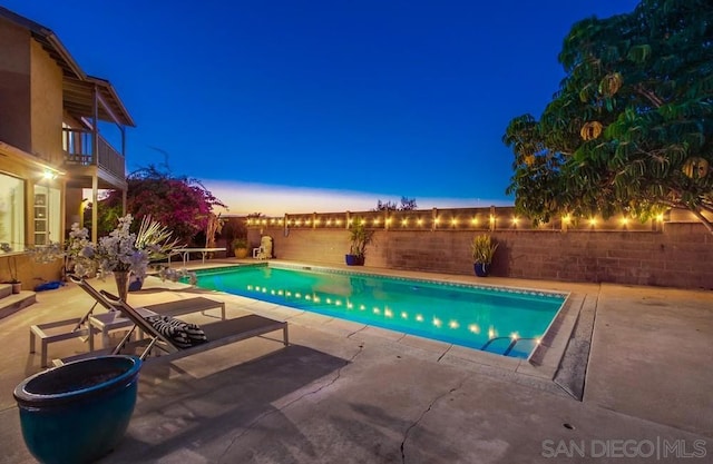 pool at dusk featuring a water view