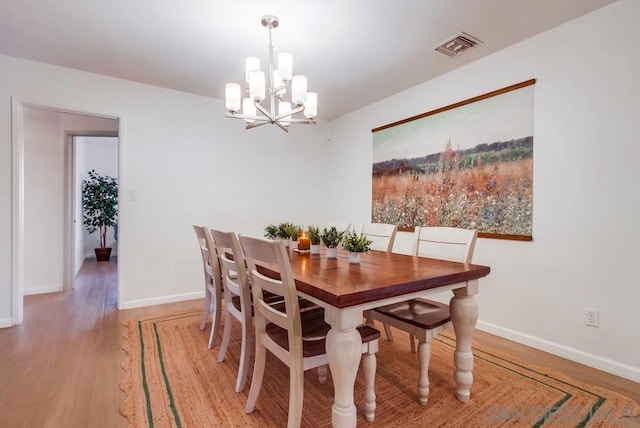 dining area with hardwood / wood-style floors and a notable chandelier