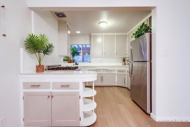 kitchen featuring stainless steel refrigerator, white cabinetry, and light hardwood / wood-style floors