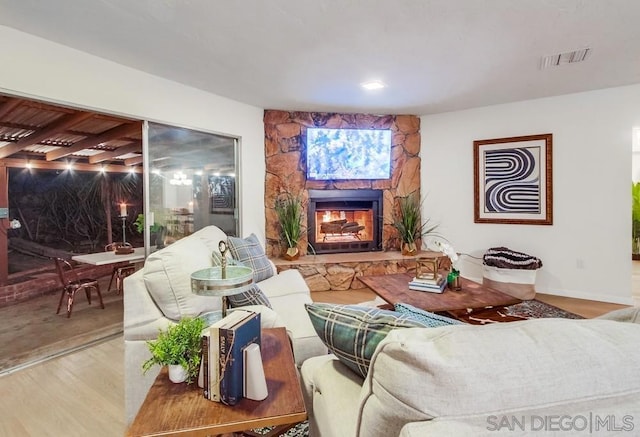 living room with a stone fireplace and wood-type flooring