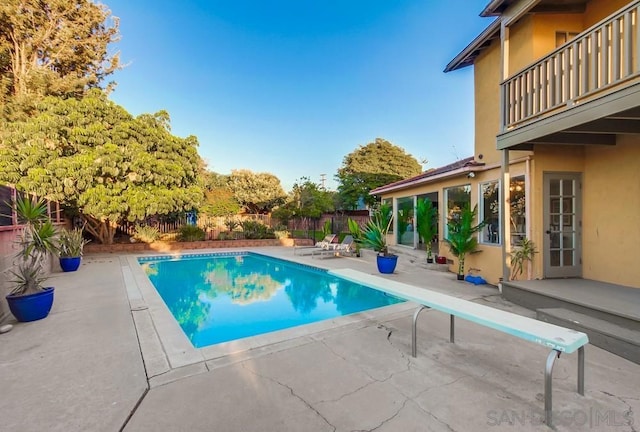 view of swimming pool featuring a diving board and a patio