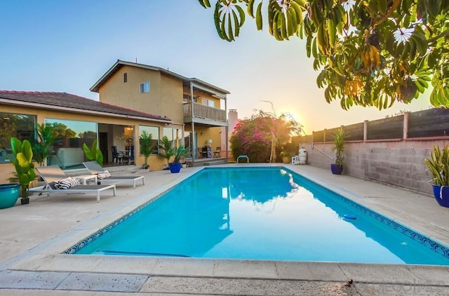 pool at dusk with a patio area