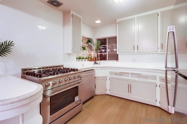 kitchen with light hardwood / wood-style floors, white cabinetry, and stainless steel appliances