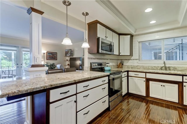 kitchen with appliances with stainless steel finishes, pendant lighting, sink, white cabinets, and kitchen peninsula