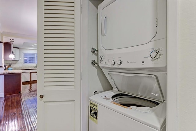 laundry room with stacked washer / drying machine and wood-type flooring