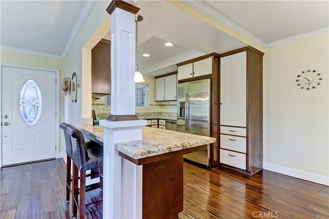 kitchen with crown molding, a kitchen breakfast bar, kitchen peninsula, and stainless steel refrigerator with ice dispenser