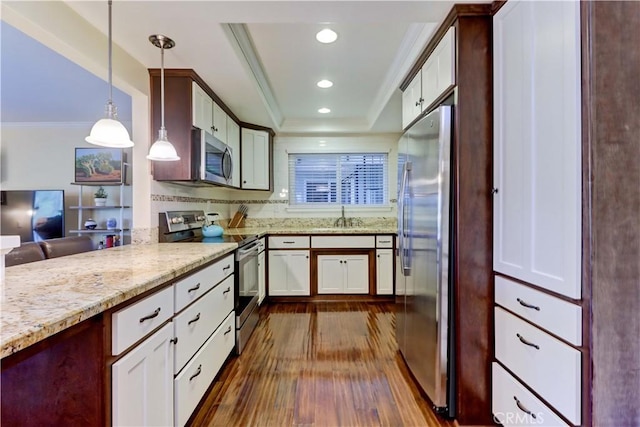 kitchen featuring sink, ornamental molding, appliances with stainless steel finishes, pendant lighting, and white cabinets