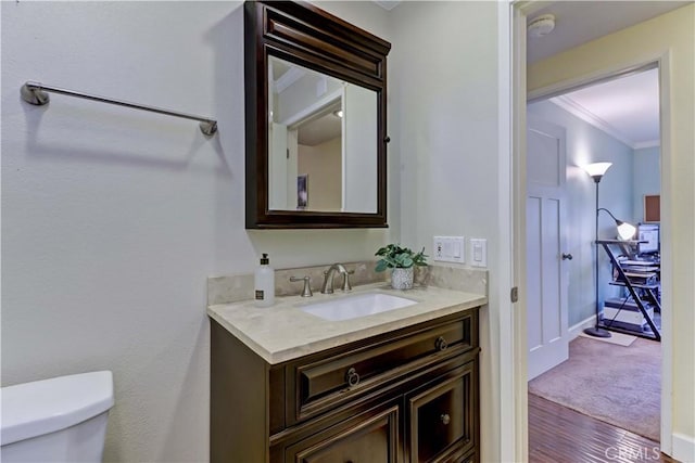 bathroom featuring vanity, crown molding, wood-type flooring, and toilet