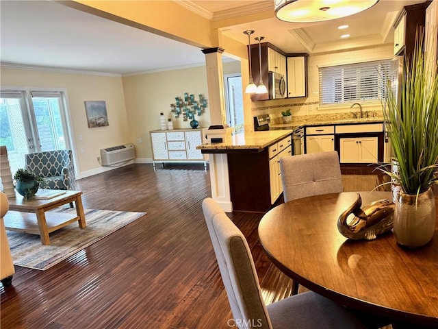 kitchen featuring decorative light fixtures, ornamental molding, stainless steel appliances, and ornate columns