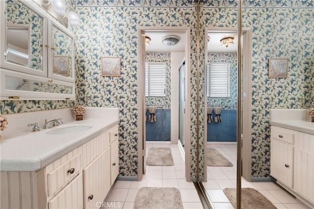 full bath featuring tile patterned floors, a stall shower, vanity, and wallpapered walls