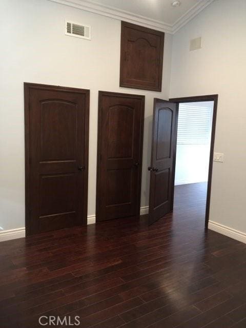 unfurnished bedroom featuring dark wood-type flooring, high vaulted ceiling, and ornamental molding