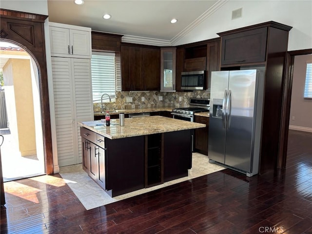 kitchen with a center island, wood-type flooring, vaulted ceiling, dark brown cabinetry, and stainless steel appliances