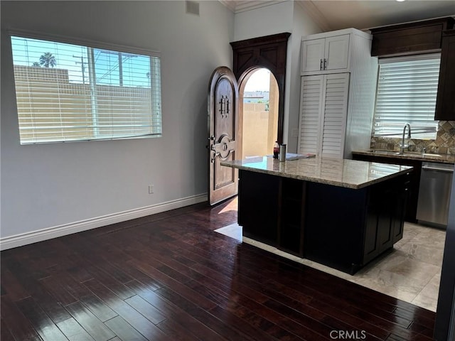 kitchen featuring stainless steel dishwasher, dark hardwood / wood-style floors, a center island, and ornamental molding