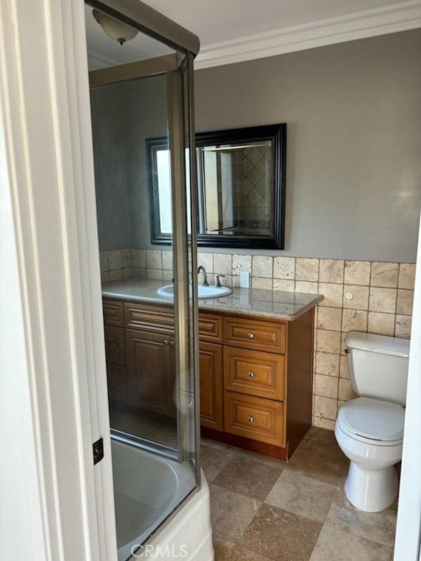 full bathroom featuring ornamental molding, vanity, tile walls, enclosed tub / shower combo, and toilet