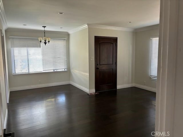 spare room with ornamental molding, dark hardwood / wood-style flooring, and a notable chandelier