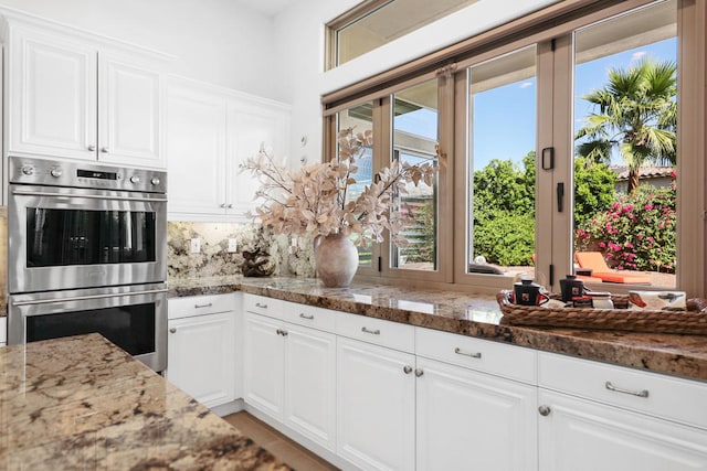 kitchen featuring white cabinetry and dark stone counters