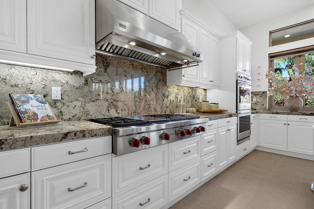 kitchen with stone counters, stainless steel appliances, extractor fan, and white cabinets